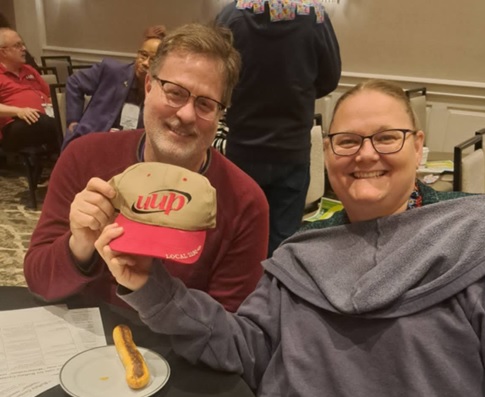 UUP Oneonta delegates smile for the camera while holding up a tan hat with the UUP logo on it