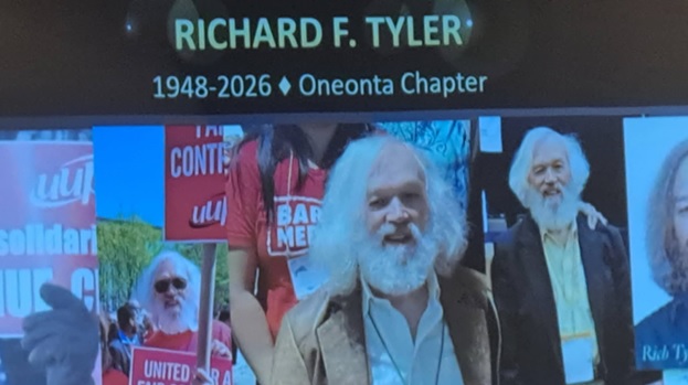 A photograph of a slide from the delegate assembly slideshow that honors Richard F. Tyler (1948-2026)