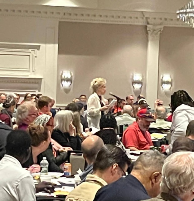 UUP Oneonta President Shirley Clark rises to honor Richard F. Tyler at the UUP Oneonta Spring Delegate Assembly, surrounded by a bunch of seated delegates.